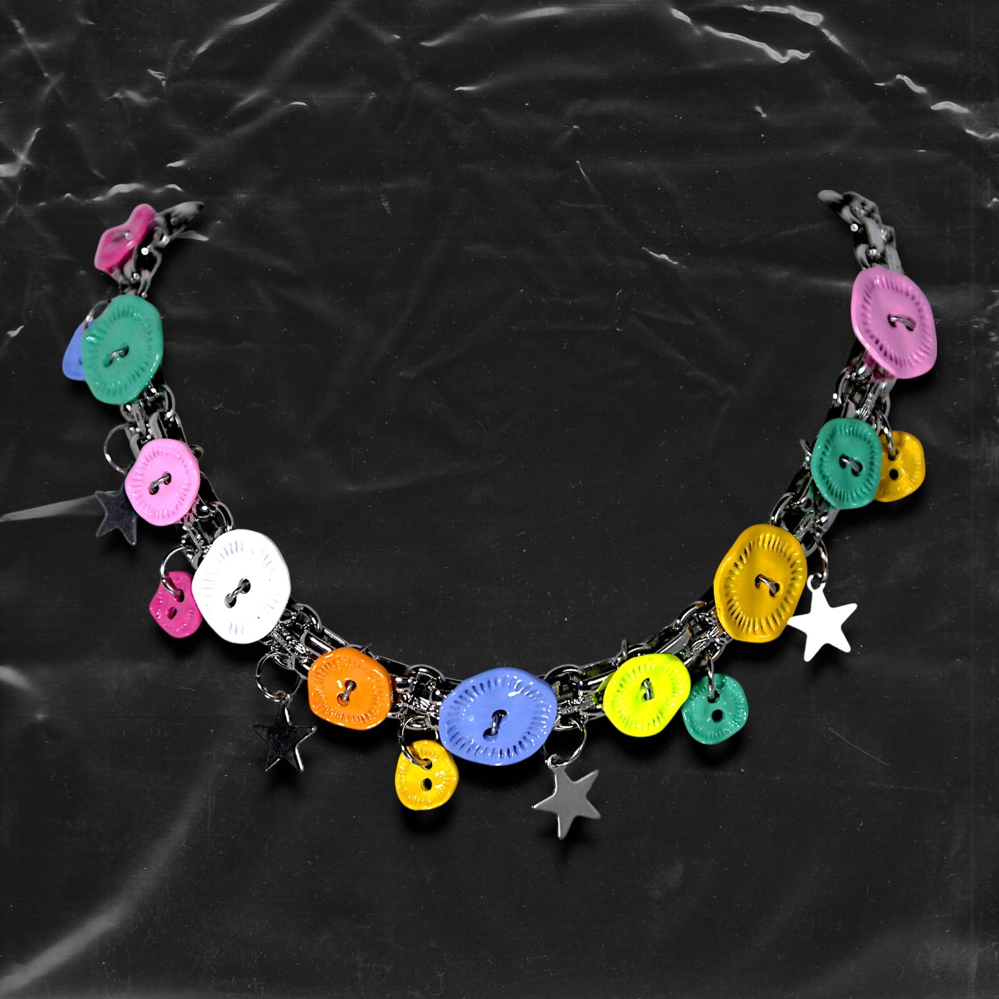 Chockychoker "Button Riot" Choker
 Crafted with a bold silver chain base, this choker is adorned with a playful mix of oversized and small multicolor vintage metal buttons and silver-toned star charms. Like a vibrant button explosion, the design fuses Y2K, gothic kawaii, and playful aesthetics ， perfect for lovers of colorful layering, creative styling, and expressive fashion.