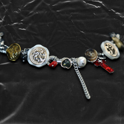Chockychoker "Dear Item" choker is a silver-based statement piece accented in red, gold, white, and green. It features seal-like silver and gold medallions, a red cross, a green heart charm, faux pearls, vintage-style metallic buttons, a long silver dangling chain, and shell-inspired pieces. Like a wearable collection of curious treasures, this piece blends fantasy, vintage, and Y2K styles—perfect for fairycore, eclectic, and narrative-driven fashion lovers.

