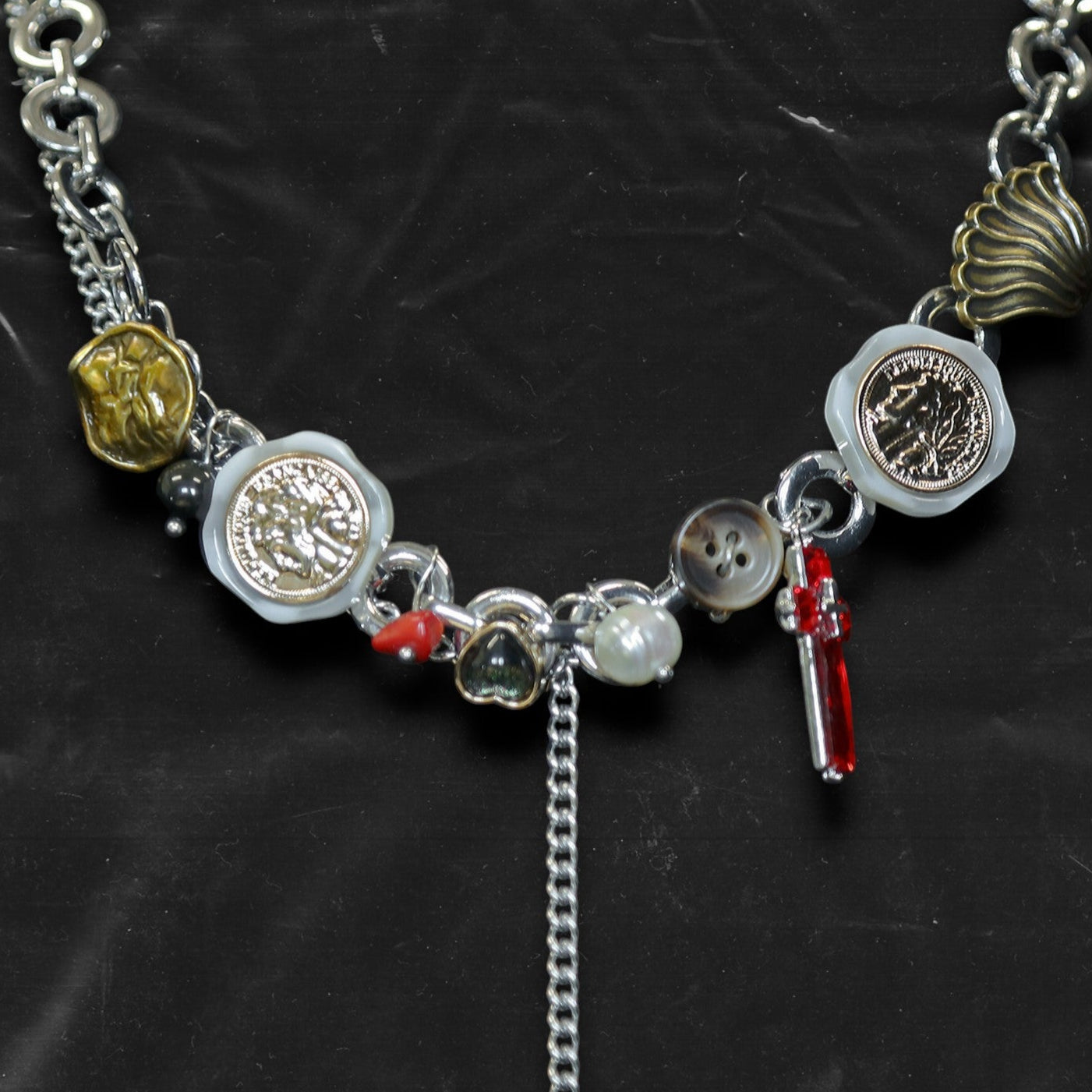 Chockychoker "Dear Item" choker is a silver-based statement piece accented in red, gold, white, and green. It features seal-like silver and gold medallions, a red cross, a green heart charm, faux pearls, vintage-style metallic buttons, a long silver dangling chain, and shell-inspired pieces. Like a wearable collection of curious treasures, this piece blends fantasy, vintage, and Y2K styles—perfect for fairycore, eclectic, and narrative-driven fashion lovers.


