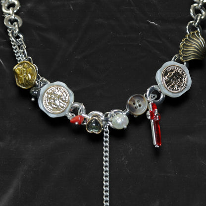 Chockychoker "Dear Item" choker is a silver-based statement piece accented in red, gold, white, and green. It features seal-like silver and gold medallions, a red cross, a green heart charm, faux pearls, vintage-style metallic buttons, a long silver dangling chain, and shell-inspired pieces. Like a wearable collection of curious treasures, this piece blends fantasy, vintage, and Y2K styles—perfect for fairycore, eclectic, and narrative-driven fashion lovers.


