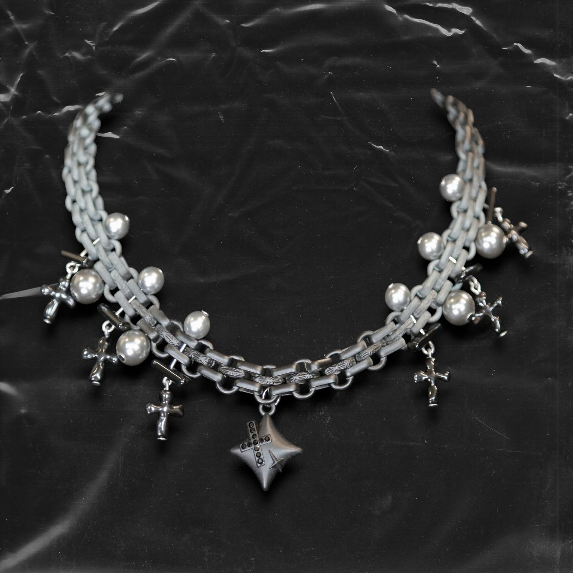 Chockychoker "Echo Unit" is a gradient silver chain choker featuring industrial-style links combined with metallic pearl beads. Multiple silver and black cross charms dangle along the chain, centered by a sculpted three-dimensional star pendant inlaid with black crystals. The overall design blends gothic, Y2K, industrial, and punk aesthetics, perfect for those drawn to dark, bold, and empowering styles.