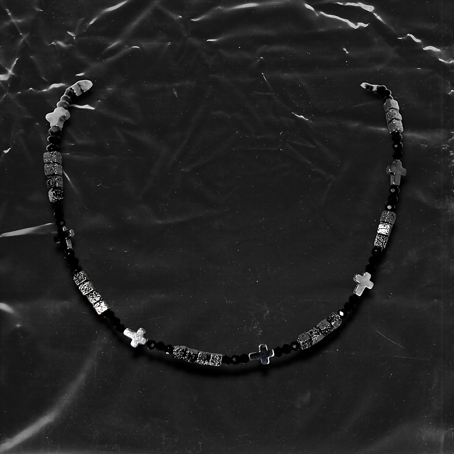 Chockychoker "Grain Script" Necklace
This necklace features a fine silver chain adorned with matte black square beads, textured metal cube spacers, and minimalist silver cross pendants. With clean lines and a cool-toned palette, it fuses gothic and dark Y2K aesthetics in a restrained yet strikingly expressive style. Perfect for lovers of dark minimalism and layered statement accessories.

