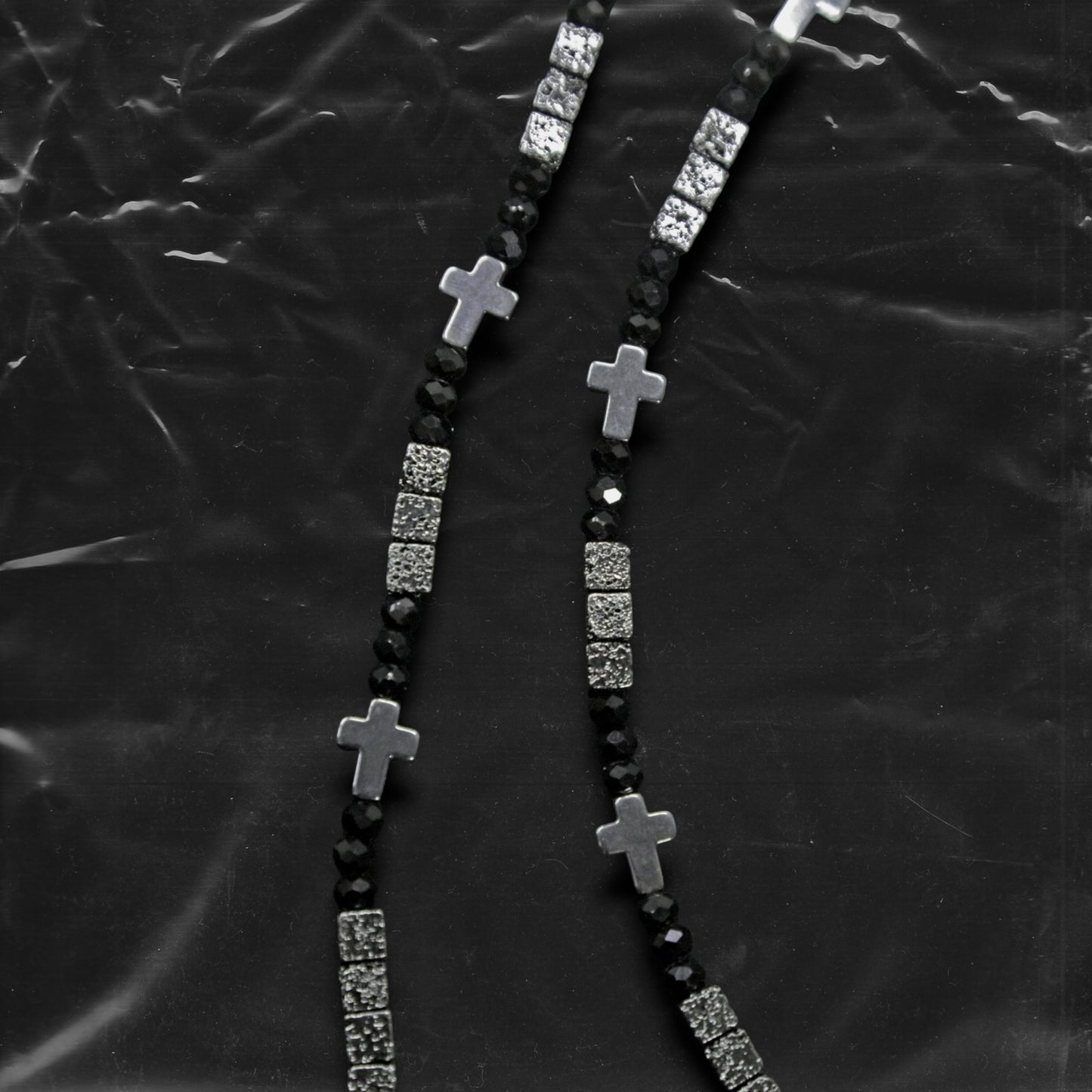 Chockychoker "Grain Script" Necklace
This necklace features a fine silver chain adorned with matte black square beads, textured metal cube spacers, and minimalist silver cross pendants. With clean lines and a cool-toned palette, it fuses gothic and dark Y2K aesthetics in a restrained yet strikingly expressive style. Perfect for lovers of dark minimalism and layered statement accessories.

