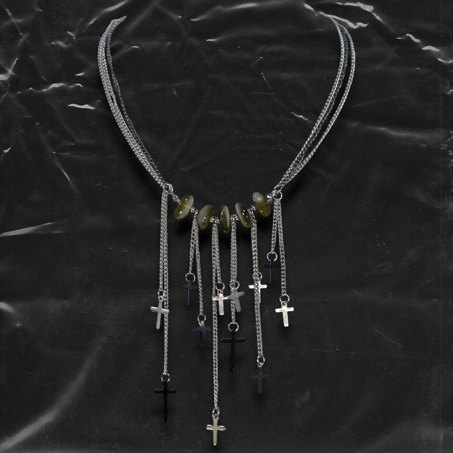 Chockychoker “Graviton Choir” Necklace is crafted from layered silver-toned fine chains, creating a fluid, multi-dimensional silhouette. The center is accented with amber glass beads, Along the lower edge, silver cross pendants are arranged in a staggered pattern. Blending gothic mystique and religious symbolism with Y2K futurism and industrial-punk edge, this piece is perfect for those drawn to dark romanticism, layered accessories, and strong visual presence in styling.
