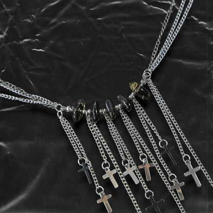 Chockychoker “Graviton Choir” Necklace is crafted from layered silver-toned fine chains, creating a fluid, multi-dimensional silhouette. The center is accented with amber glass beads, Along the lower edge, silver cross pendants are arranged in a staggered pattern. Blending gothic mystique and religious symbolism with Y2K futurism and industrial-punk edge, this piece is perfect for those drawn to dark romanticism, layered accessories, and strong visual presence in styling.
