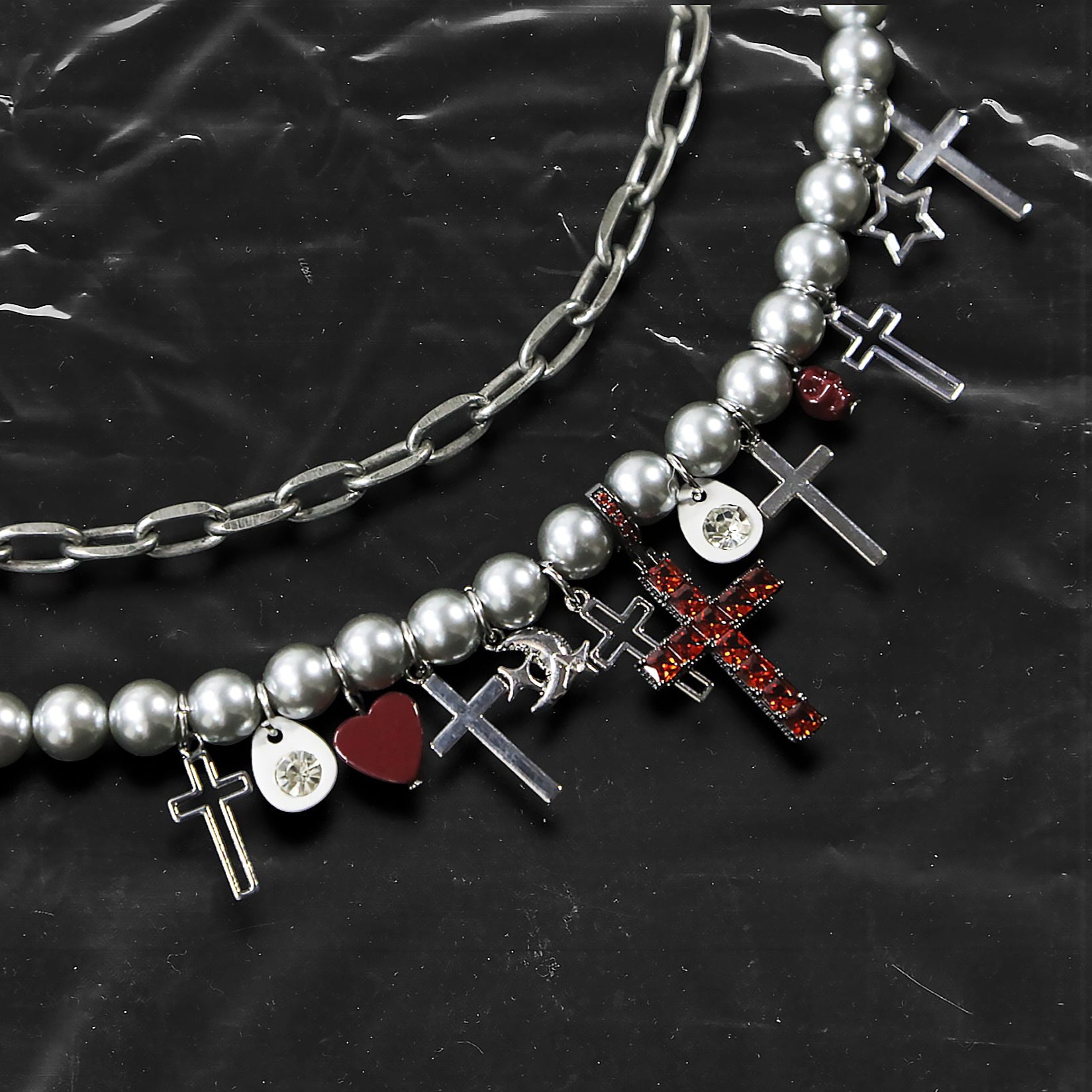 Chockychoker “ Metal Creed ” is a Double-layer choker necklace featuring metallic silver beads and a chunky alloy chain, adorned with a central cross pendant inlaid with sparkling red crystals. Additional charms include alloy cross pendants,  red heart, crescent moon, and hollow star. This statement choker is ideal for gothic, punk, glam-rock, Y2K, and edgy alternative fashion styles.
