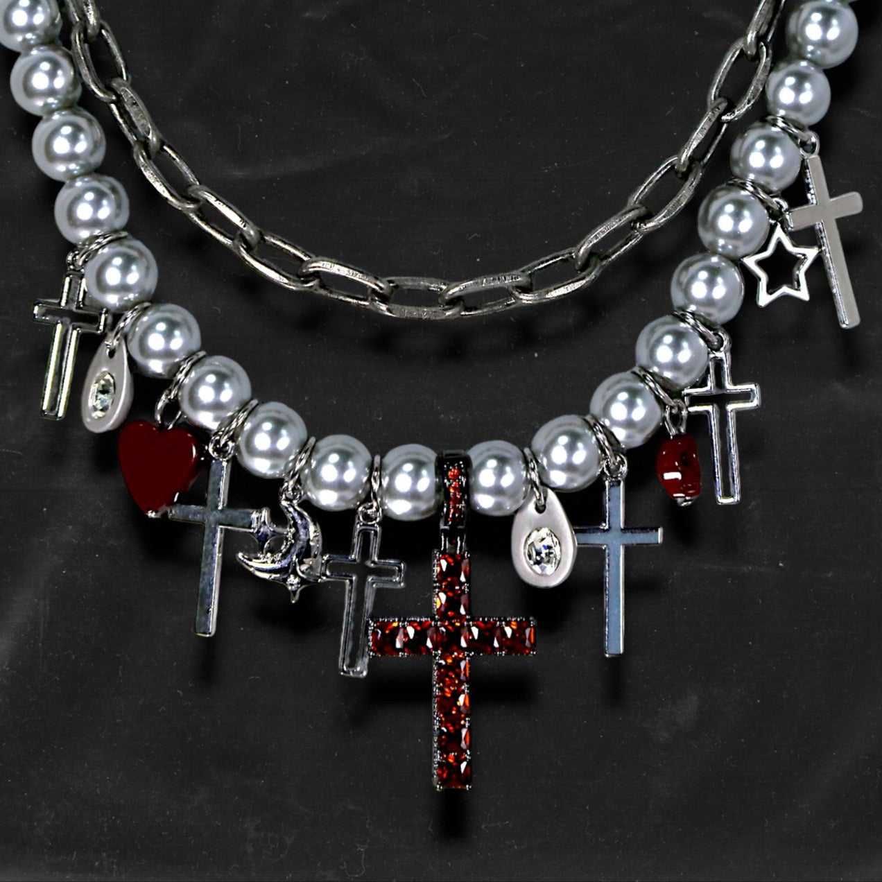 Chockychoker “ Metal Creed ” is a Double-layer choker necklace featuring metallic silver beads and a chunky alloy chain, adorned with a central cross pendant inlaid with sparkling red crystals. Additional charms include alloy cross pendants,  red heart, crescent moon, and hollow star. This statement choker is ideal for gothic, punk, glam-rock, Y2K, and edgy alternative fashion styles.
