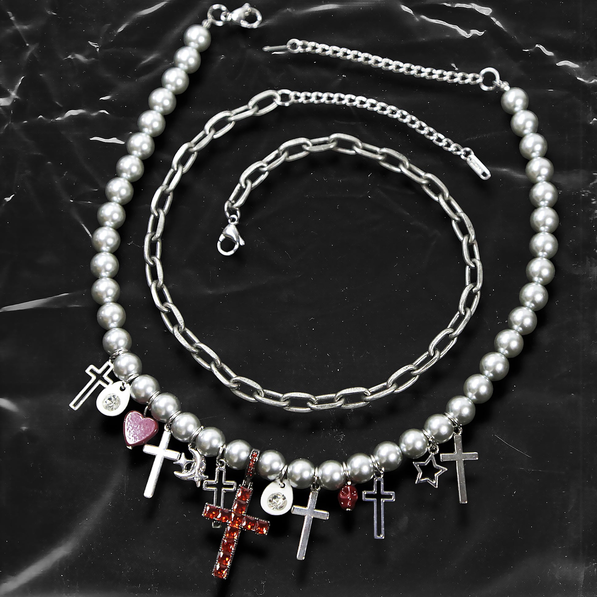 Chockychoker “ Metal Creed ” is a Double-layer choker necklace featuring metallic silver beads and a chunky alloy chain, adorned with a central cross pendant inlaid with sparkling red crystals. Additional charms include alloy cross pendants,  red heart, crescent moon, and hollow star. This statement choker is ideal for gothic, punk, glam-rock, Y2K, and edgy alternative fashion styles.
