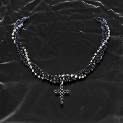 Chockychoker “Midnight Stitch” choker features a layered design made of black beads and silver-tone faux pearls, centered with a black rhinestone-studded cross pendant. The necklace blends gothic and Y2K influences with bold contrast and structured detail. A perfect statement piece for gothic, punk, alt, emo, and fashion-forward styles.