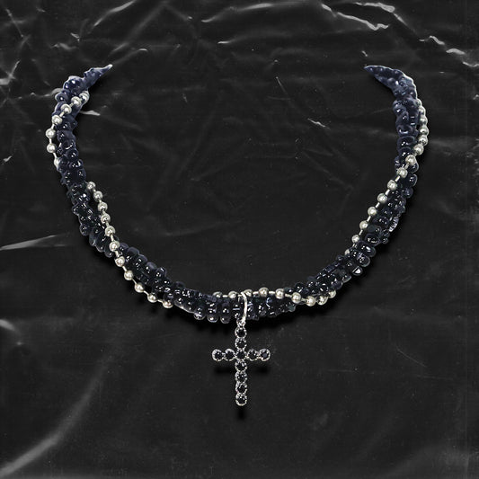 Chockychoker “Midnight Stitch” choker features a layered design made of black beads and silver-tone faux pearls, centered with a black rhinestone-studded cross pendant. The necklace blends gothic and Y2K influences with bold contrast and structured detail. A perfect statement piece for gothic, punk, alt, emo, and fashion-forward styles.