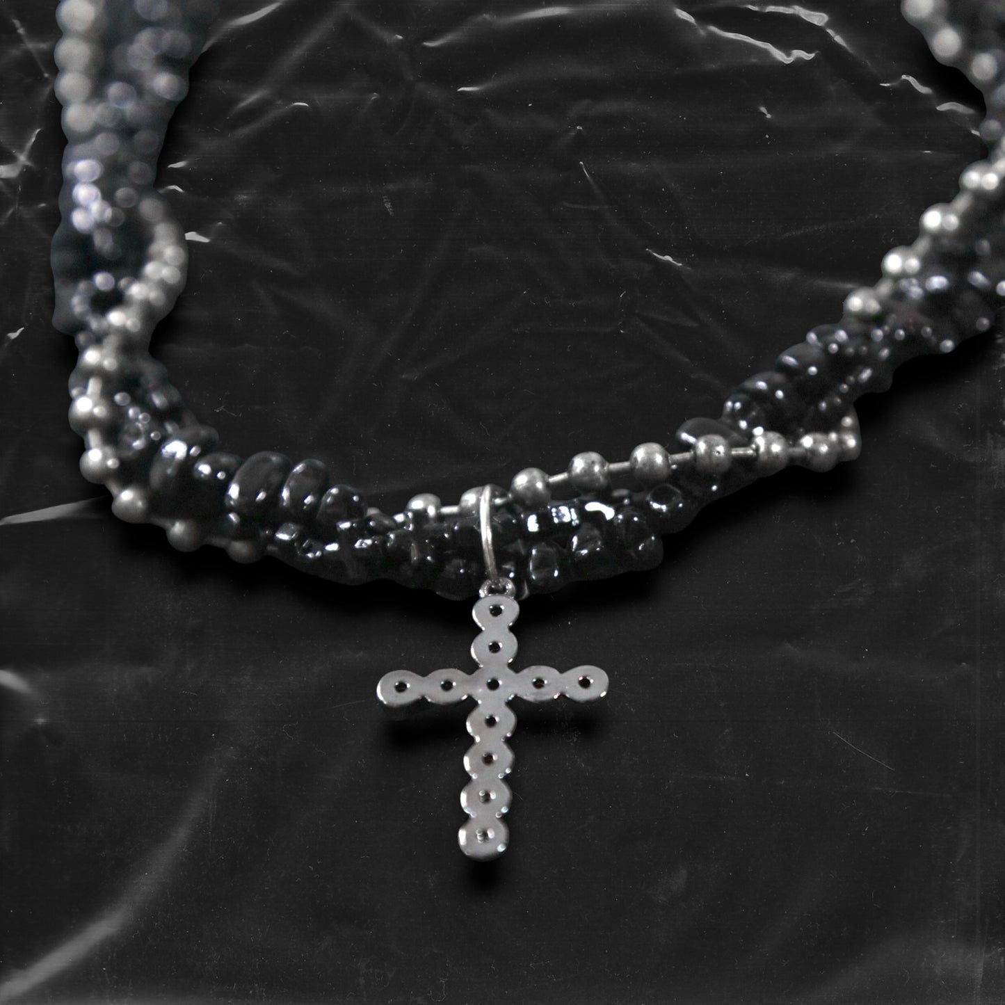 Chockychoker “Midnight Stitch” choker features a layered design made of black beads and silver-tone faux pearls, centered with a black rhinestone-studded cross pendant. The necklace blends gothic and Y2K influences with bold contrast and structured detail. A perfect statement piece for gothic, punk, alt, emo, and fashion-forward styles.