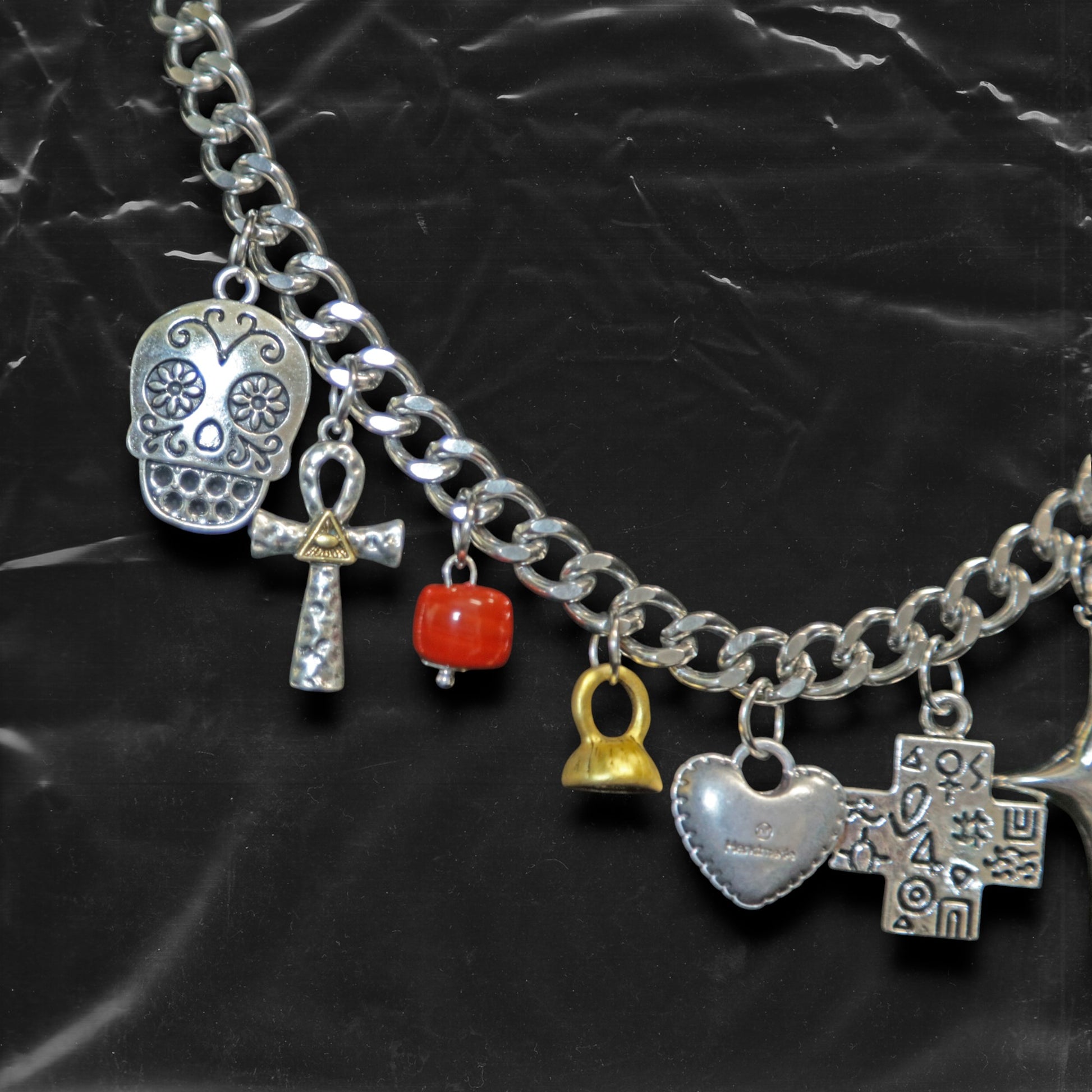 Chockychoker "Moonlit Relic" choker featuring a thick silver-tone chain adorned with eclectic dangling charms, including a crystal-eyed skull, metallic hearts, engraved cross, cosmic star, abstract rings, red gem heart, and vintage-style miniatures like a bell, shell, and keys. This mixed-media statement piece blends Y2K, gothic, alt, and symbolic aesthetics for bold and expressive styling.
