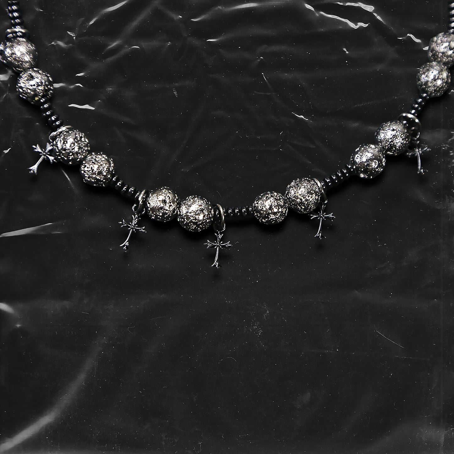 Chockychoker “Nova Chain II ” is a Black gothic choker featuring silver-black alloy beads with a textured, bumpy finish, black plastic cross charms, and black seed beads interwoven as connectors. Ideal for goth, punk, grunge, and alt fashion lovers seeking bold handmade statement jewelry.
