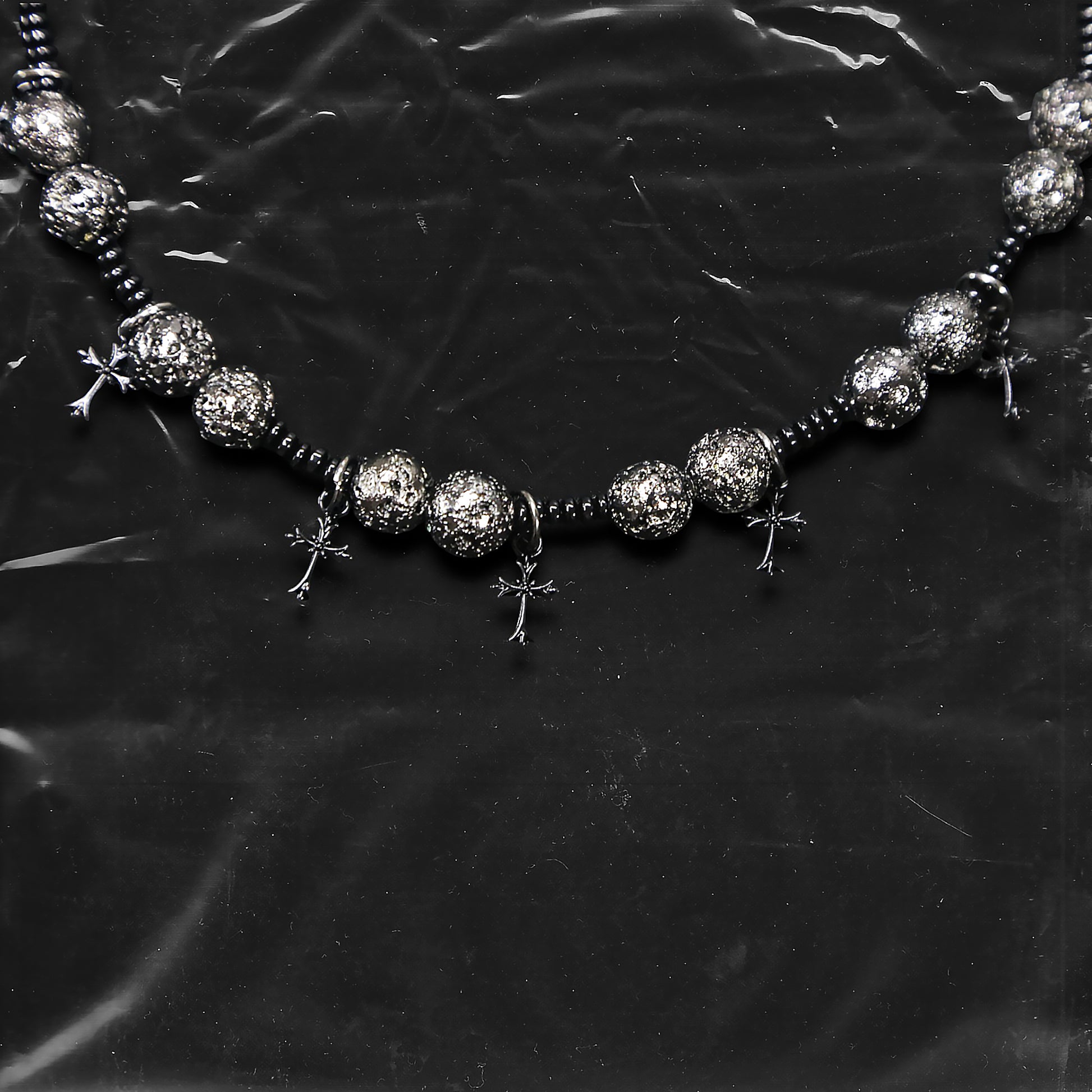 Chockychoker “Nova Chain II ” is a Black gothic choker featuring silver-black alloy beads with a textured, bumpy finish, black plastic cross charms, and black seed beads interwoven as connectors. Ideal for goth, punk, grunge, and alt fashion lovers seeking bold handmade statement jewelry.
