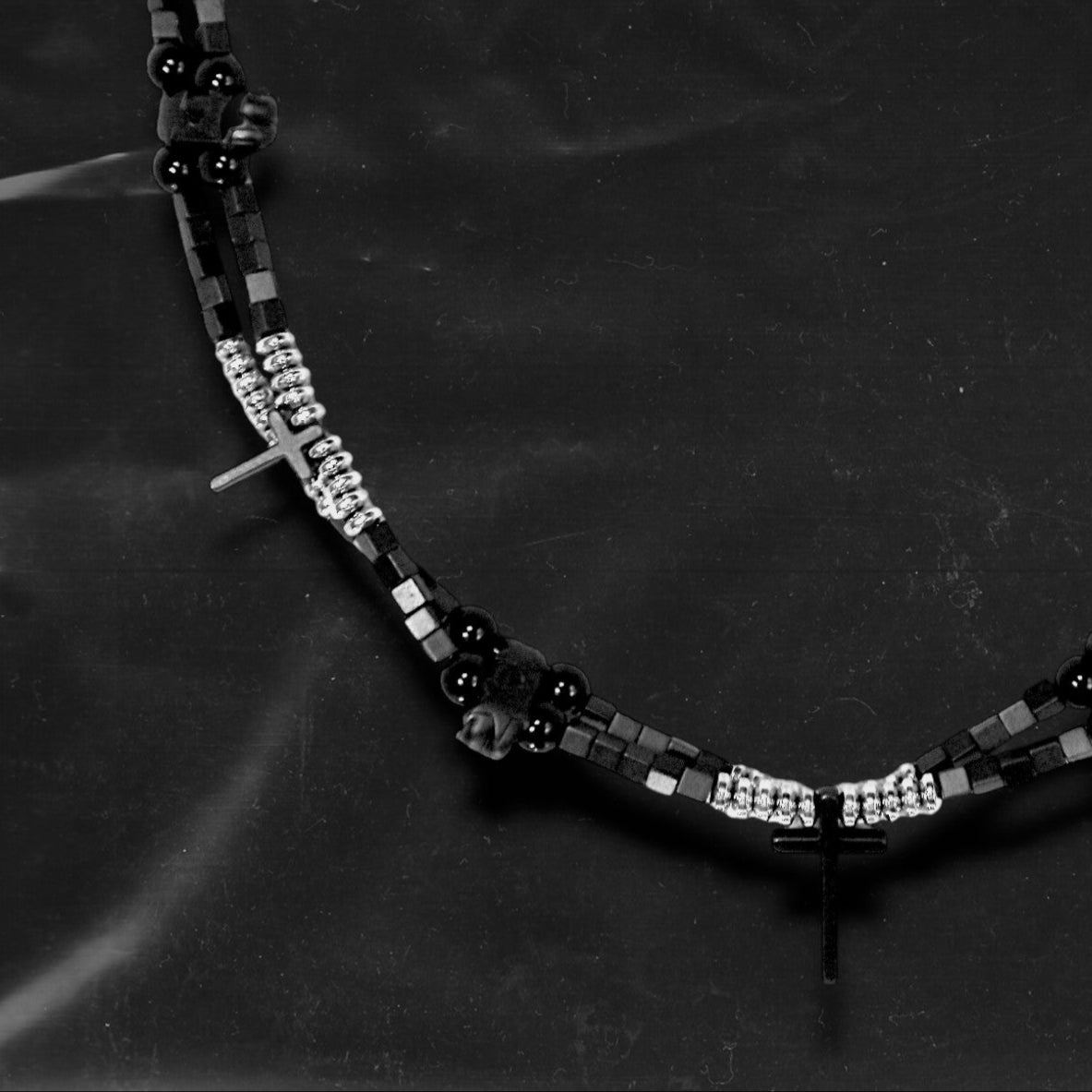 Chockychoker “Obsidian Code” is a meticulously constructed double layered necklace featuring interwoven black and silver gradient square beads, accented with metallic silver rounds and black beads for a cool, shadowy palette. Adorned with a series of small silver and black cross pendants, while black star-shaped charms add an extra layer of gothic detailing. Blending Y2K, darkwear, punk, and futuristic aesthetics, seeking edgy, gender-neutral accessories with strong streetwear appeal.