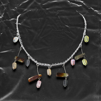 The Chockychoker "Stone Chime" choker features a delicate silver chain as its base, adorned with irregularly shaped colorful glass beads. These beads come in soft macaron tones lavender, mint green, buttery yellow, peachy pink, and amber brown with translucent , reminiscent of stones swaying in a breeze like wind chimes.The design draws inspiration from the playful color aesthetics of Y2K, the whimsical fairycore universe, and the imperfect charm of handcrafted jewelry