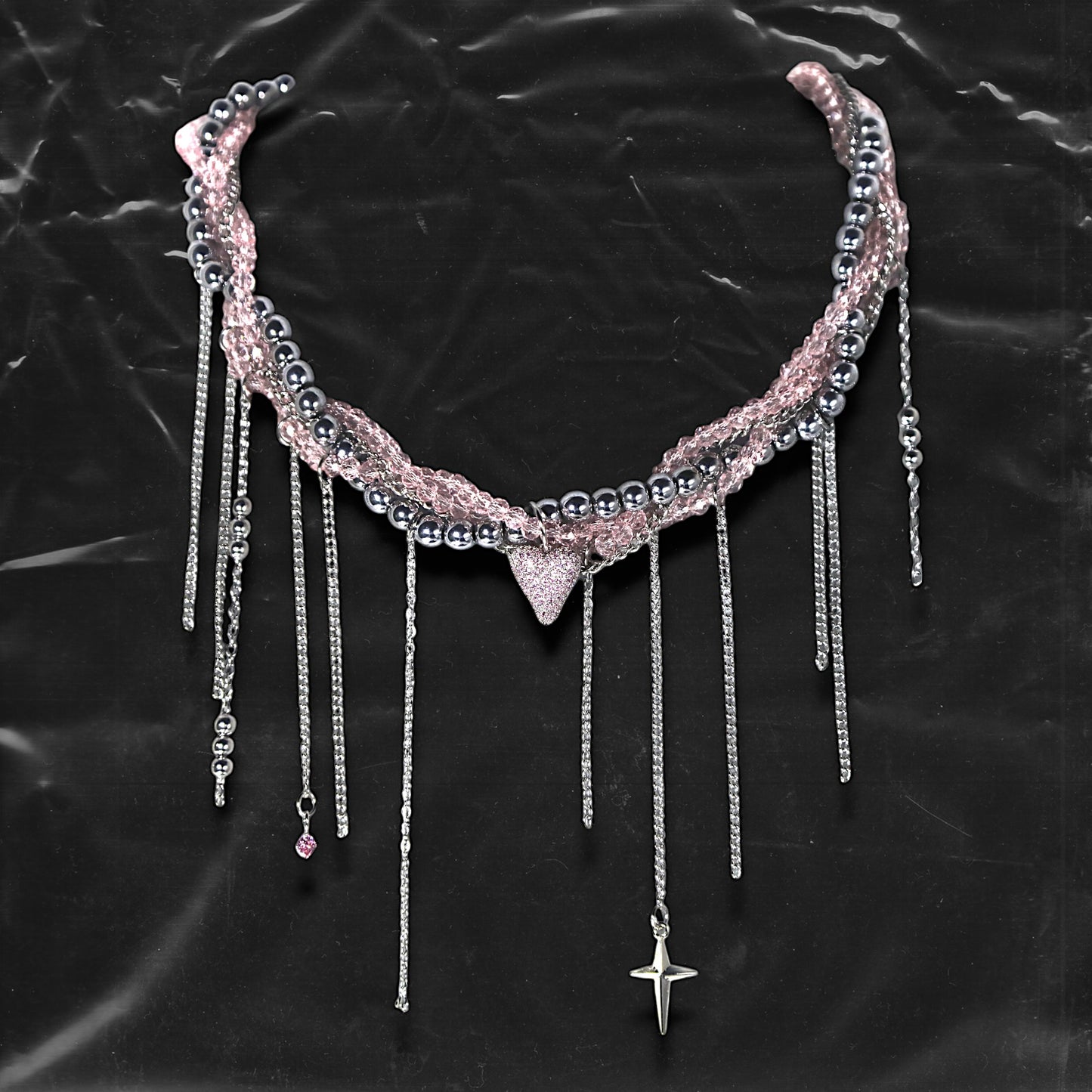 Chockychoker “ Sugarglow ” is a Double-layer twisted choker combining pink knit yarn and metallic silver alloy beads, adorned with a central heart-shaped charm inlaid with pink crystals. The necklace features dangling silver chains, transparent pink crystal drops, and a single star charm, evoking both sweetcore and edgy glam aesthetics. Perfect for lovers of Y2K revival, coquette fashion, Harajuku streetwear, Materials include silver-tone alloy, faux crystals, acrylic yarn, and metal chains.