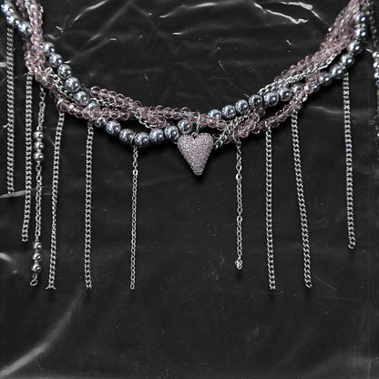 Chockychoker “ Sugarglow ” is a Double-layer twisted choker combining pink knit yarn and metallic silver alloy beads, adorned with a central heart-shaped charm inlaid with pink crystals. The necklace features dangling silver chains, transparent pink crystal drops, and a single star charm, evoking both sweetcore and edgy glam aesthetics. Perfect for lovers of Y2K revival, coquette fashion, Harajuku streetwear, Materials include silver-tone alloy, faux crystals, acrylic yarn, and metal chains.