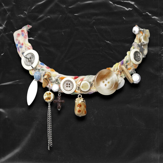 Chockychoker “Teddy Patch II” is Colorful handcrafted yarn choker featuring a glazed brown ceramic bear charm, layered with a mix of oversized vintage-style buttons in white, cream, and brown tones, including . Embellished with faux pearls, natural wooden pieces, a small black cross pendant, textured silver-tone chains, shell-shaped charms, and polished blue stone beads. This statement necklace is perfect for fans of Y2K, grunge, indie, soft goth, alt fashion.