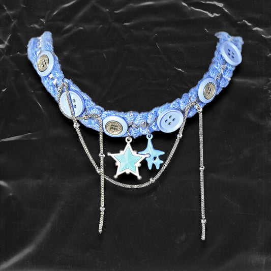 Chockychoker "Blue Save Point"  handmade choker featuring  blue star pendants in resin   finish, accented with silver-tone chains of mixed texture, and secured onto a woven light blue yarn base. Decorated with multiple blue and silver-tone buttons along the band. This piece combines  star motifs , creating a unique blend of sweet-cool , alt, Harajuku, cyberpop, and soft punk aesthetics.  Materials include yarn, alloy buttons, silver-tone metal chains, and enamel resin charms.
