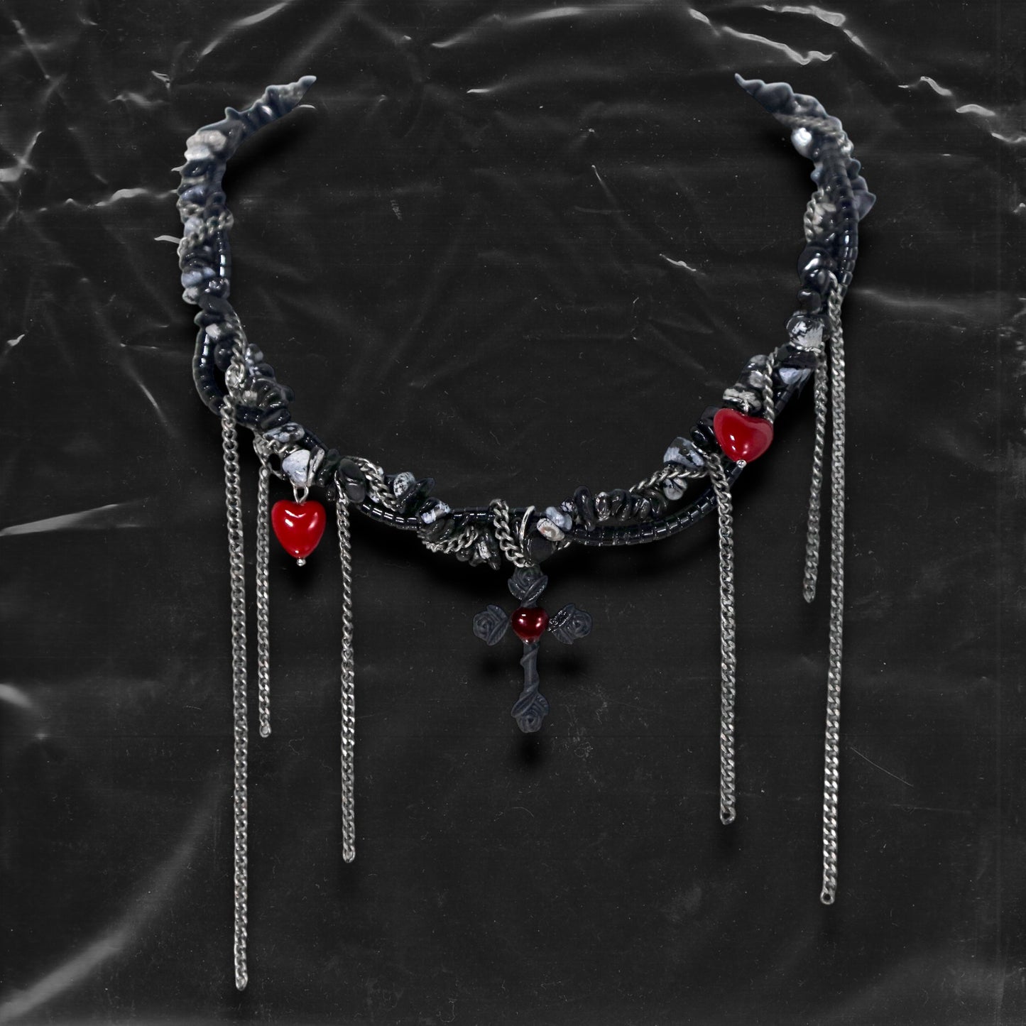 Chockychoker “Oath Object” is a gothic-inspired black ribbon choker featuring textured silver embellishments, dramatic silver-tone chain fringe, deep red heart charms, and a matte black cross pendant with floral details. Combining dark romance with edgy elements, this handcrafted piece blends punk, goth, emo, and Y2K aesthetics—perfect for those who love statement jewelry with emotional and symbolic undertones.
