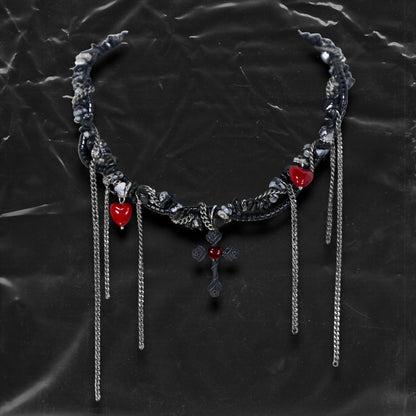 Chockychoker “Oath Object” is a gothic-inspired black ribbon choker featuring textured silver embellishments, dramatic silver-tone chain fringe, deep red heart charms, and a matte black cross pendant with floral details. Combining dark romance with edgy elements, this handcrafted piece blends punk, goth, emo, and Y2K aesthetics—perfect for those who love statement jewelry with emotional and symbolic undertones.
